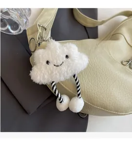 Detail of a white plush cloud charm with smiley face on a light blue leather bag