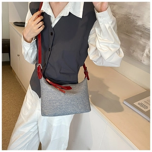 Chic grey underarm bag with red leather strap shown on a model for daily commute