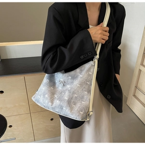 Detail of blue denim tote bag with white bow pattern and elegant metal bow clasp