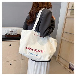 Detail view of white canvas tote bag with red and blue Crème Glacée embroidery
