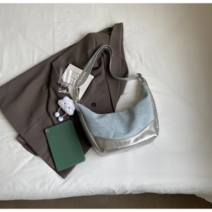 Chic hobo bag with denim patchwork and silver mirror finish, styled with cloud charm