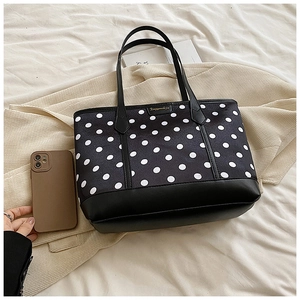 Fashionable black and white polka dot tote bag with minimalist shoulder straps in daily use