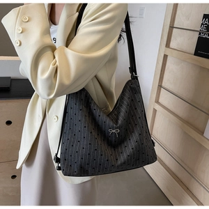 Detail of grey tote bag with striped heart pattern and silver bow on model in office setting