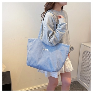 Blue and white striped large tote bag with Magic Pocket label detail worn on shoulder