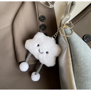 Close-up of a white plush cloud charm with a smiling face on a denim shoulder bag
