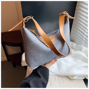 Detail of grey textured hobo bag with brown leather straps and adjustable buckle