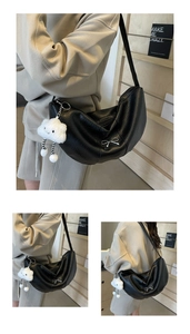 Macro detail of black leather half-moon bag featuring silver bow and plush cloud charm