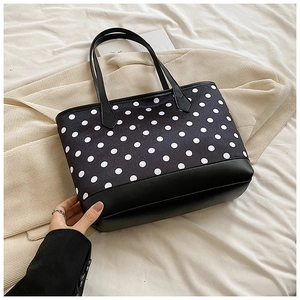 Close-up of stylish polka dot tote bag with leather拼接 detailing and shoulder straps