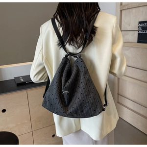 Detail of gray backpack with stripe heart pattern and silver bow charm on a model