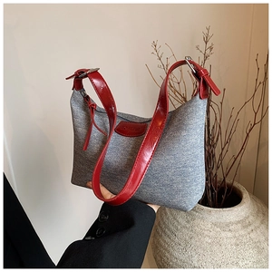 Detail of grey denim shoulder bag with red leather trim and 'NO FILTER' patch