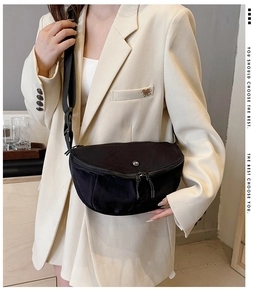 Detail of a black crescent crossbody bag with adjustable wide strap on a model