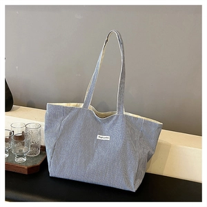 Close-up of blue and white striped canvas tote bag with embroidered Magic Pocket label