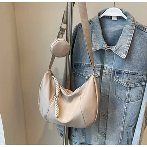 Detail of beige crescent shoulder bag with wide strap and matching round coin purse