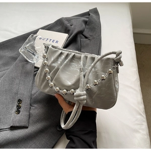 Detail einer silbernen Falten-Schultertasche mit Metallperlenkette und Knotengriff-Design