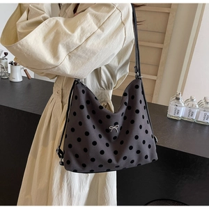 Detail of polka dot tote bag featuring a silver bow accent and large black spots
