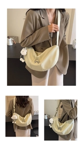 Detail of cream crescent crossbody bag with silver bow and plush sheep pendant