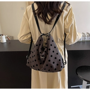 Detail of grey polka dot backpack featuring a decorative silver bow pendant on zipper