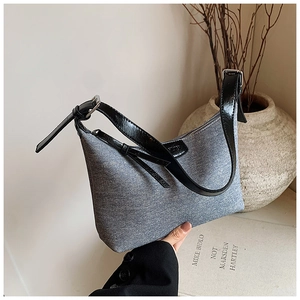 Close-up of light blue denim hobo bag with black patent leather strap and silver buckle