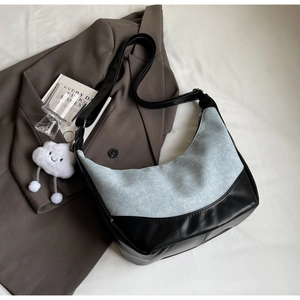 Detail of denim and black leather patchwork hobo bag with plush cloud charm