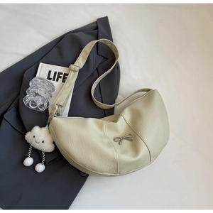 Detail of cream crescent crossbody bag with silver bow accent and cloud charm