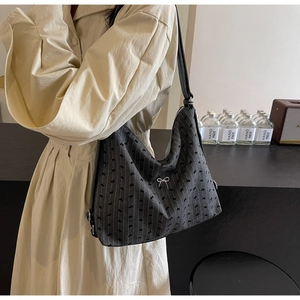 Detail of pinstripe hobo bag with bow patterns and metal buckle on a model shoulder