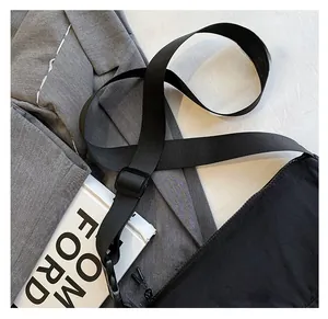 Close-up of black nylon crossbody bag with wide strap and minimalist logo on suit jacket