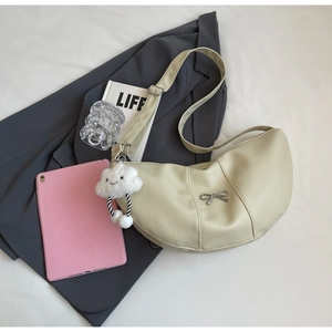 Detail view of cream crescent crossbody bag with silver bow and cloud plush charm