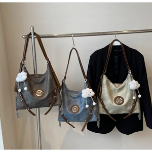 Three large Hobo bags in dark gray, blue, and white with M logo and cloud charms