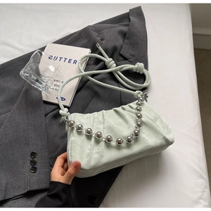 Detail der mintgrünen Cloud-Bag mit Falten, Silberperlenkette und Riemen auf einem Blazer