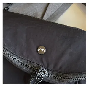 Detail of waterproof nylon fabric with black dual metal zippers and wave logo emblem