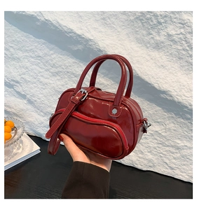 Detail of burgundy glossy patent leather crossbody bag with decorative buckle and zipper