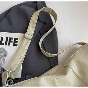 Detail of off-white lychee grain leather handbag with silver buckle and zipper closure