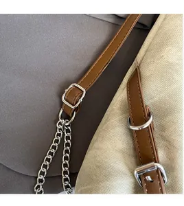 Detail of adjustable dark brown leather shoulder strap with silver metal chain and buckle