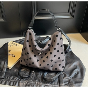 Detail of grey polka dot tote bag with silver bow charm on a leather jacket