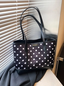Chic black polka dot tote bag with contrast leather handles on a modern background