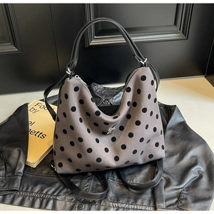 Detail of grey polka dot hobo bag with silver bow accent and adjustable leather strap