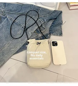 Mini canvas crossbody bag for cell phone showing size comparison with a smartphone