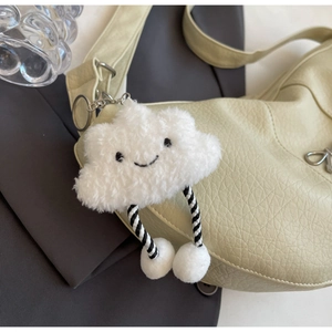 Close-up of fluffy white cloud plush keychain charm on a green textured leather bag