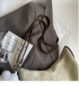 Detail of green fabric tote bag with brown leather straps on a grey suit background