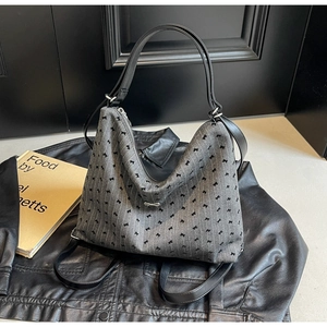Detail of grey jacquard tote bag with bow patterns on black leather jacket backdrop