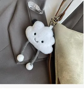 Detail of a plush cloud charm with long striped legs hanging on a stylish beige handbag