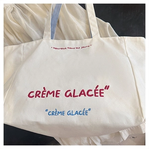 Detail of canvas tote bag with Crème Glacée text and blue striped inner handles