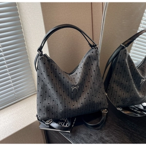 Close-up of grey striped tote with heart patterns and a silver metallic bow logo