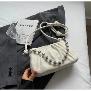 Detail der gerafften Cloud-Bag mit silberner Perlenkette auf dunkelgrauem Blazer-Stoff
