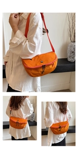 Close-up detail of a bright orange nylon crescent crossbody bag with black dual zippers