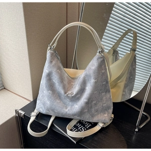 Detail view of light blue denim tote with white bow patterns and silver bow charm detail