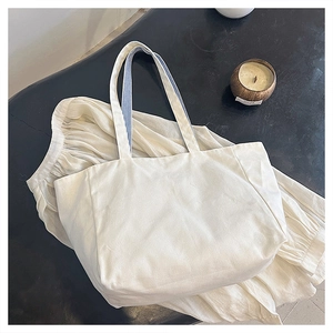 Close-up of the large white canvas tote bag with blue striped lining on its shoulder strap
