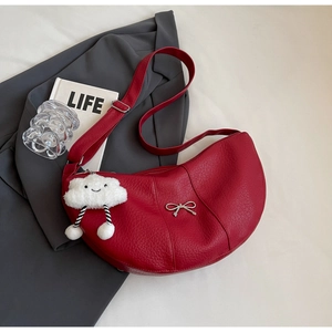 Detail of red lychee leather dumpling bag with silver bow and cloud plush charm