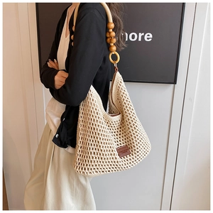 Detail of hand-woven crochet tote bag with wooden bead straps and leather patch