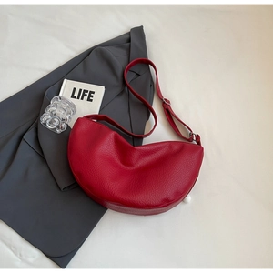 Top view of a red crescent shoulder bag with lychee grain texture and adjustable strap